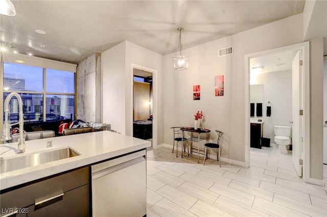 kitchen featuring decorative light fixtures, dishwasher, and sink