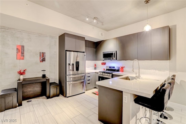 kitchen with gray cabinets, decorative light fixtures, a kitchen breakfast bar, kitchen peninsula, and stainless steel appliances