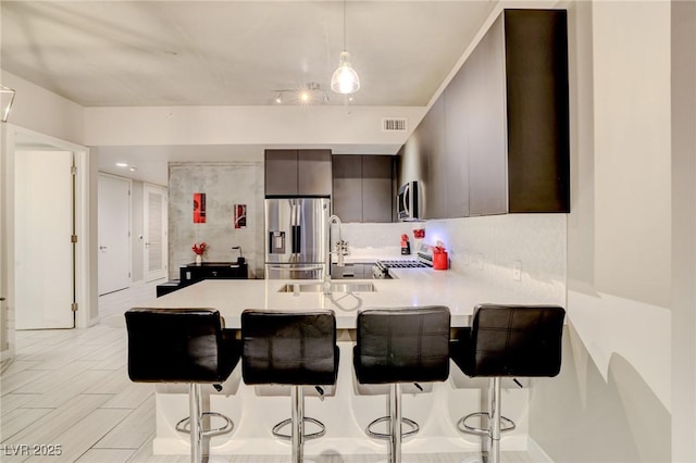 kitchen with sink, a breakfast bar area, hanging light fixtures, stainless steel appliances, and kitchen peninsula