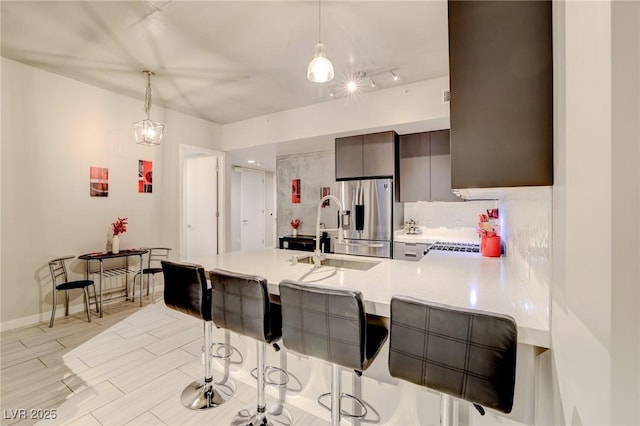 kitchen featuring decorative light fixtures, stainless steel fridge, a kitchen breakfast bar, and kitchen peninsula