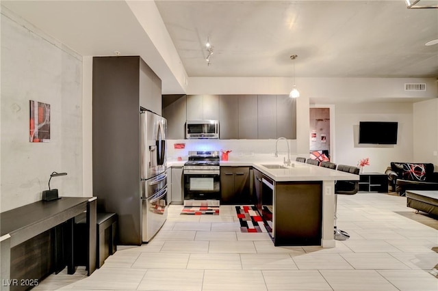 kitchen featuring pendant lighting, rail lighting, a breakfast bar, stainless steel appliances, and kitchen peninsula