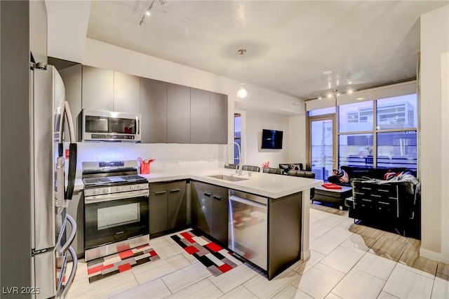 kitchen with appliances with stainless steel finishes, pendant lighting, sink, light tile patterned floors, and kitchen peninsula