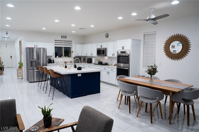 kitchen with white cabinetry, a kitchen bar, a center island with sink, and appliances with stainless steel finishes