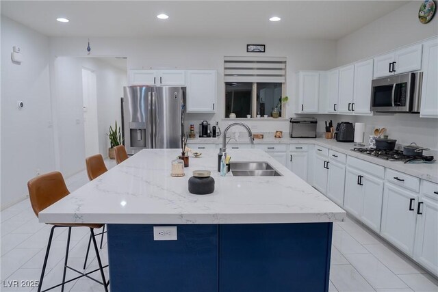 kitchen featuring sink, a breakfast bar, appliances with stainless steel finishes, a kitchen island with sink, and white cabinets