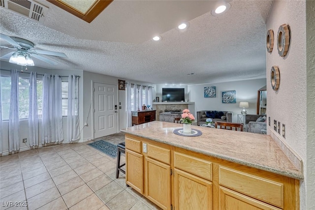 kitchen with light brown cabinetry, light tile patterned floors, a textured ceiling, and ceiling fan