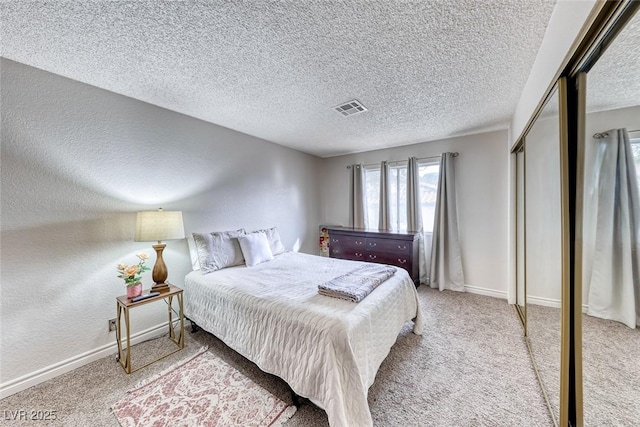 carpeted bedroom featuring a textured ceiling and a closet