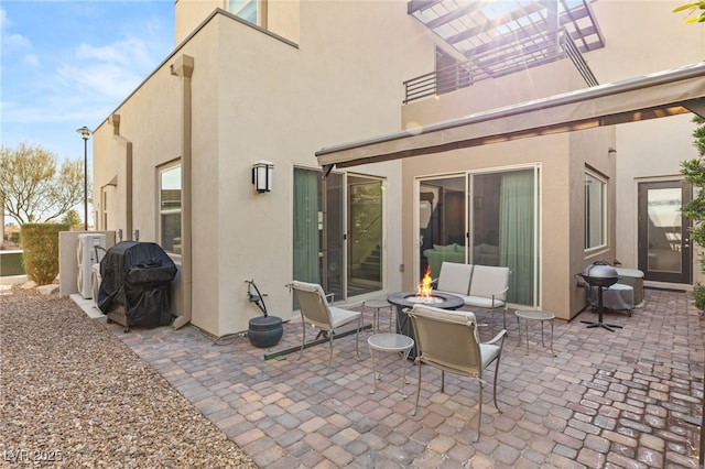 back of house with an outdoor fire pit and a patio