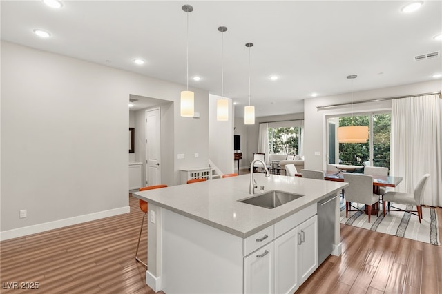 kitchen with sink, white cabinetry, hanging light fixtures, a center island with sink, and dishwasher