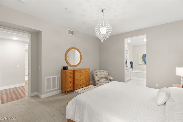 carpeted bedroom with ensuite bathroom and a chandelier