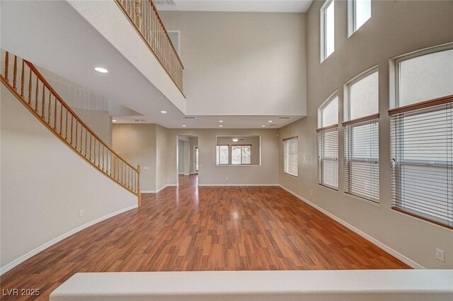 unfurnished living room featuring hardwood / wood-style floors and a towering ceiling