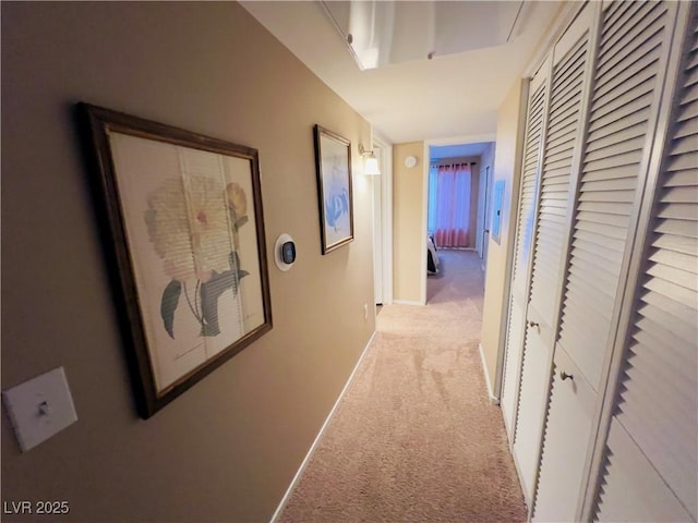 hall with baseboards and light colored carpet