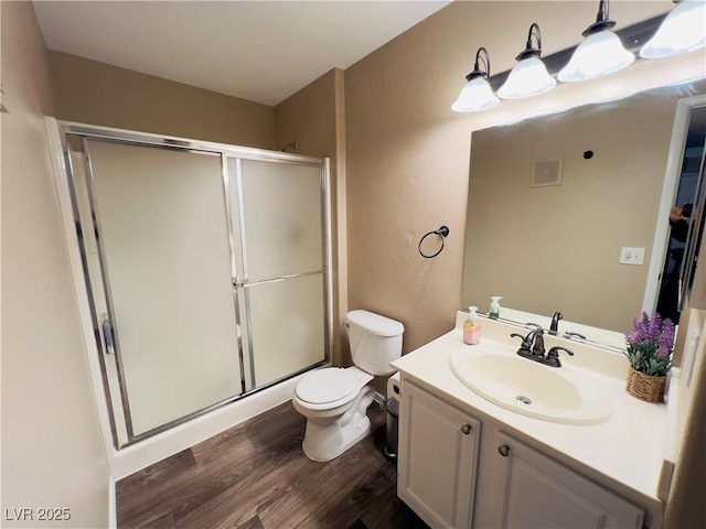 bathroom featuring visible vents, toilet, wood finished floors, and a shower stall