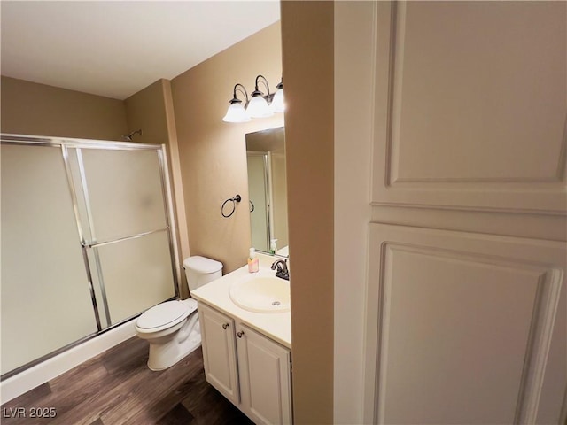 bathroom with vanity, a shower stall, toilet, and wood finished floors