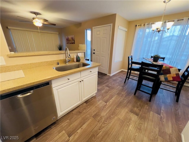 kitchen with pendant lighting, a sink, wood finished floors, white cabinets, and dishwasher