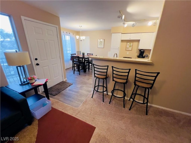 kitchen with white cabinetry, a peninsula, a breakfast bar area, and a healthy amount of sunlight