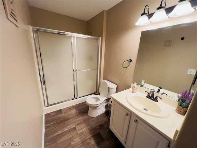 bathroom featuring visible vents, a shower stall, toilet, wood finished floors, and vanity