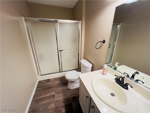 full bath with a shower with door, baseboards, toilet, wood finished floors, and vanity