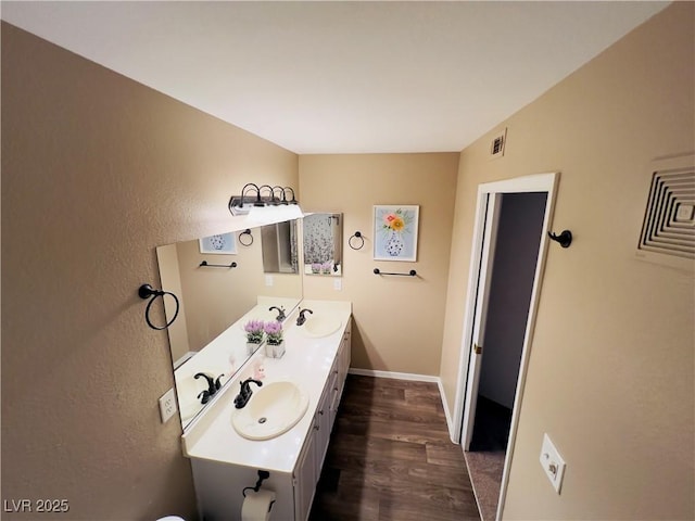 bathroom with visible vents, wood finished floors, baseboards, and a sink