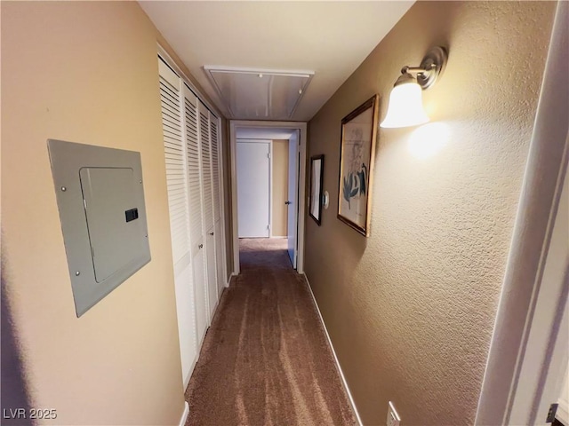 corridor featuring carpet flooring, attic access, electric panel, and a textured wall