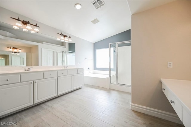 bathroom with lofted ceiling, independent shower and bath, wood-type flooring, and vanity