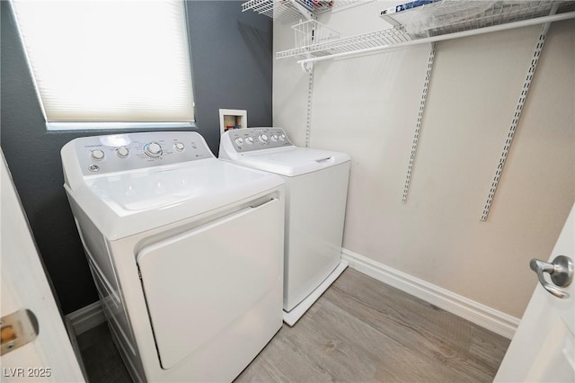 laundry area featuring washing machine and clothes dryer and light wood-type flooring