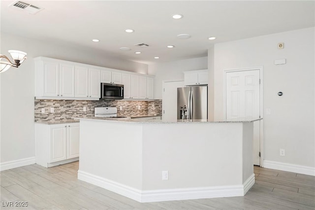 kitchen featuring appliances with stainless steel finishes, white cabinetry, backsplash, a kitchen island with sink, and light hardwood / wood-style floors