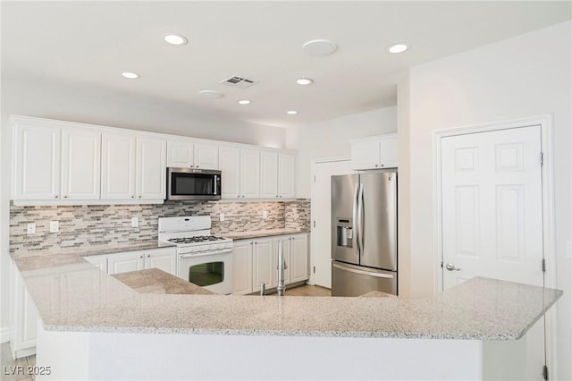 kitchen featuring stainless steel appliances, light stone counters, white cabinets, decorative backsplash, and kitchen peninsula