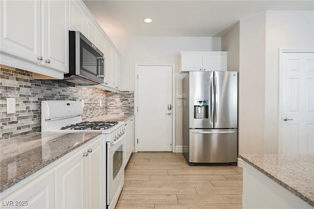 kitchen with white cabinetry, decorative backsplash, appliances with stainless steel finishes, and light stone counters