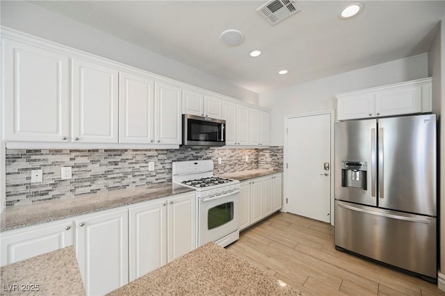 kitchen with white cabinetry, decorative backsplash, stainless steel appliances, and light hardwood / wood-style floors