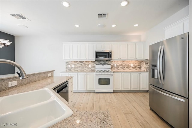 kitchen with sink, white cabinetry, tasteful backsplash, stainless steel appliances, and light hardwood / wood-style floors