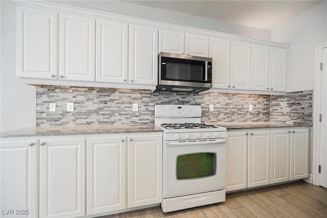 kitchen with white cabinetry, light stone counters, light wood-type flooring, white gas range oven, and backsplash