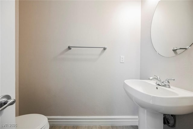 bathroom featuring wood-type flooring, toilet, and sink