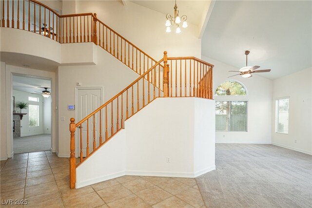 stairway with ceiling fan with notable chandelier, high vaulted ceiling, and carpet