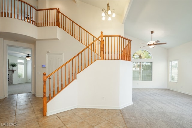 staircase featuring carpet, ceiling fan with notable chandelier, and high vaulted ceiling