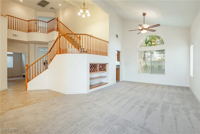 unfurnished living room with ceiling fan with notable chandelier, light carpet, and high vaulted ceiling