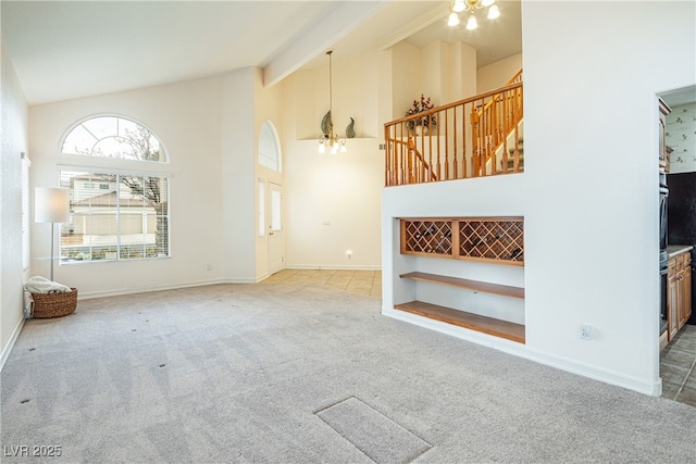 unfurnished living room featuring light carpet, beamed ceiling, high vaulted ceiling, and a chandelier