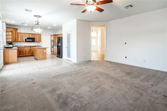 kitchen with decorative light fixtures, a center island, light carpet, and black appliances