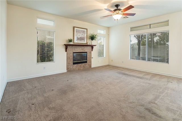 unfurnished living room featuring a tile fireplace, ceiling fan, and carpet flooring