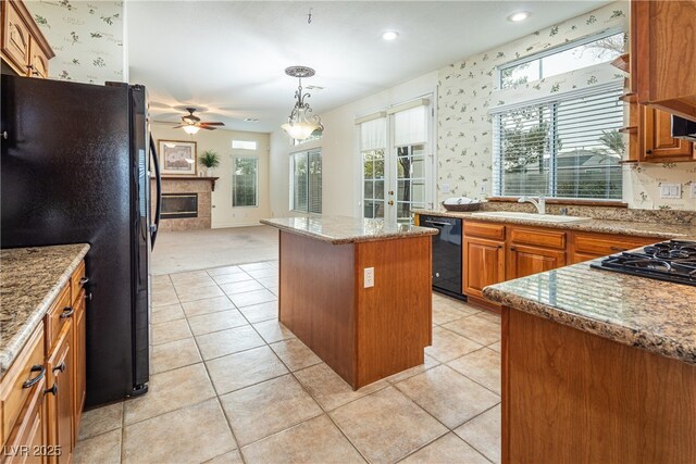 kitchen with light tile patterned flooring, sink, a center island, hanging light fixtures, and black appliances