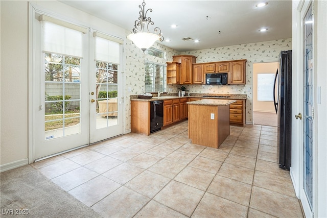 kitchen featuring pendant lighting, a kitchen island, black appliances, light tile patterned flooring, and french doors