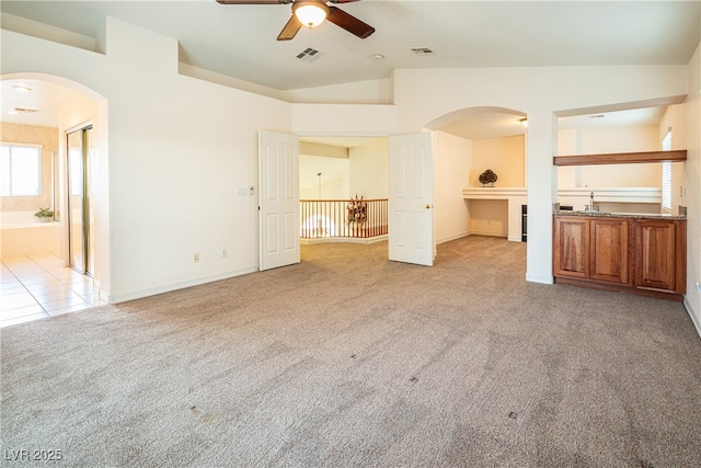 unfurnished living room with light carpet, sink, vaulted ceiling, and ceiling fan