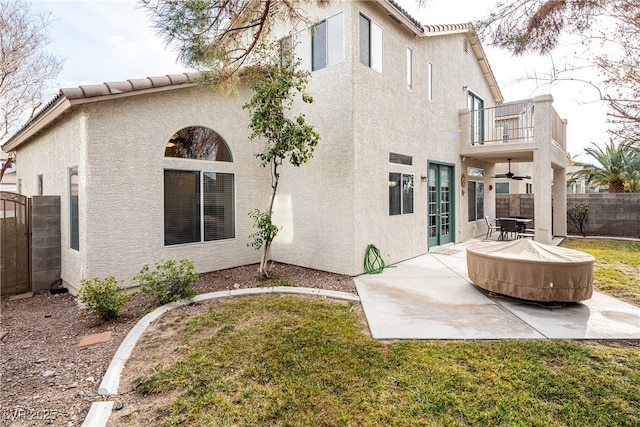 back of house featuring ceiling fan, a balcony, a yard, and a patio