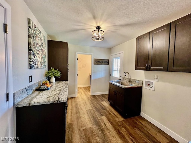 kitchen with dark brown cabinetry, light stone countertops, sink, and hardwood / wood-style floors