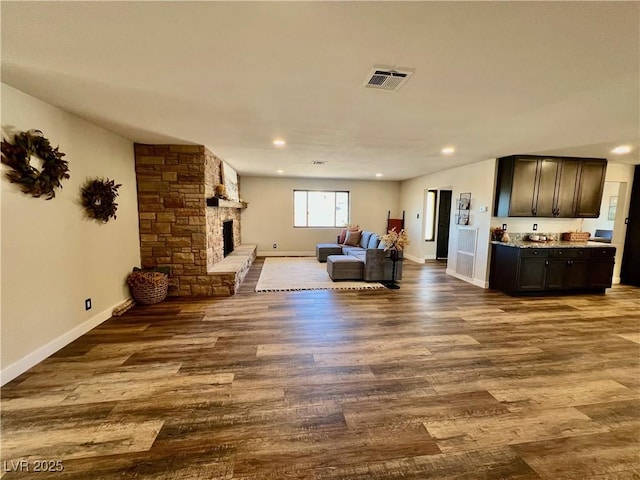 unfurnished living room featuring hardwood / wood-style floors and a stone fireplace