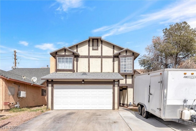 english style home with stucco siding, a shingled roof, concrete driveway, a garage, and a wall mounted air conditioner