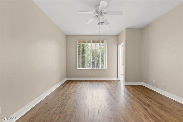 spare room featuring hardwood / wood-style floors, a ceiling fan, and baseboards