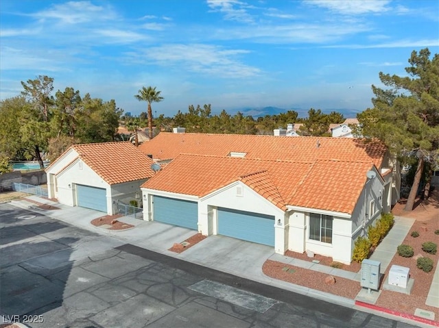 mediterranean / spanish-style home featuring concrete driveway, an attached garage, a tile roof, and stucco siding