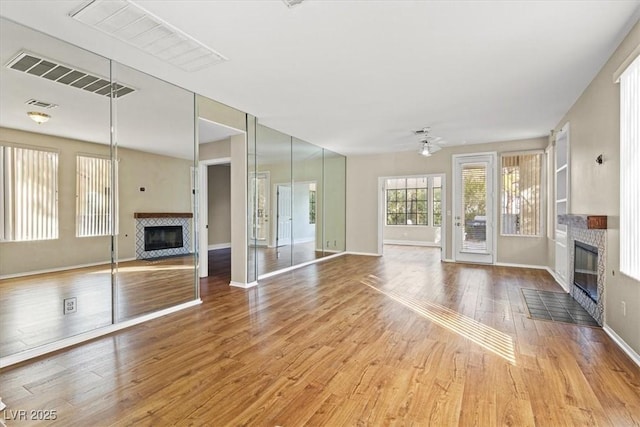 unfurnished living room with wood finished floors, a fireplace with flush hearth, and visible vents