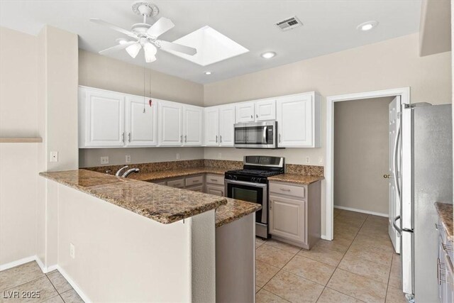 kitchen with stainless steel appliances, white cabinetry, dark stone counters, and kitchen peninsula