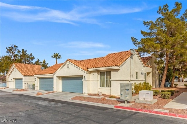 mediterranean / spanish-style house featuring an attached garage, driveway, a tile roof, and stucco siding